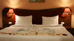 A hotel room with a large bed, two bedside lamps, and a painting on the wall. - Legend Hotel (Beirut)