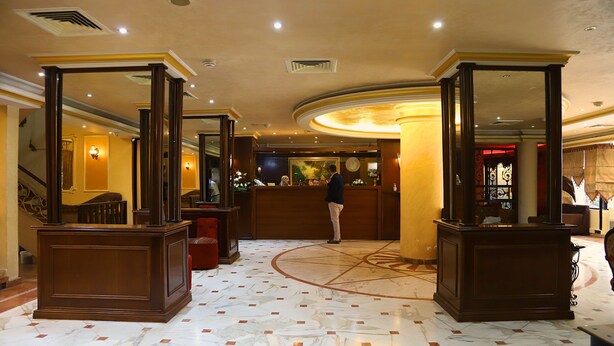 A lobby with marble flooring, wooden reception desk, and a staircase. - Legend Hotel (Beirut)