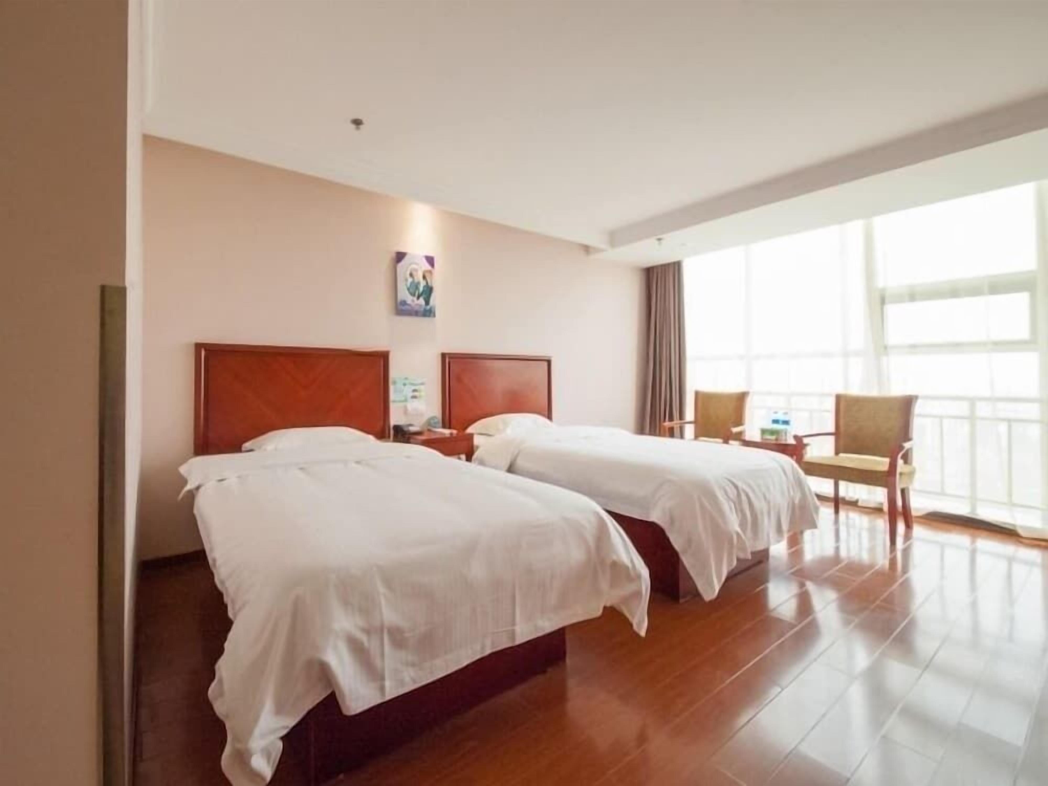 Ein Hotelzimmer mit zwei Betten, einem Schreibtisch und einem Stuhl.