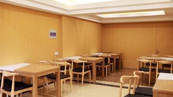 A conference room with multiple wooden tables and chairs, a whiteboard, and a ceiling light fixture.