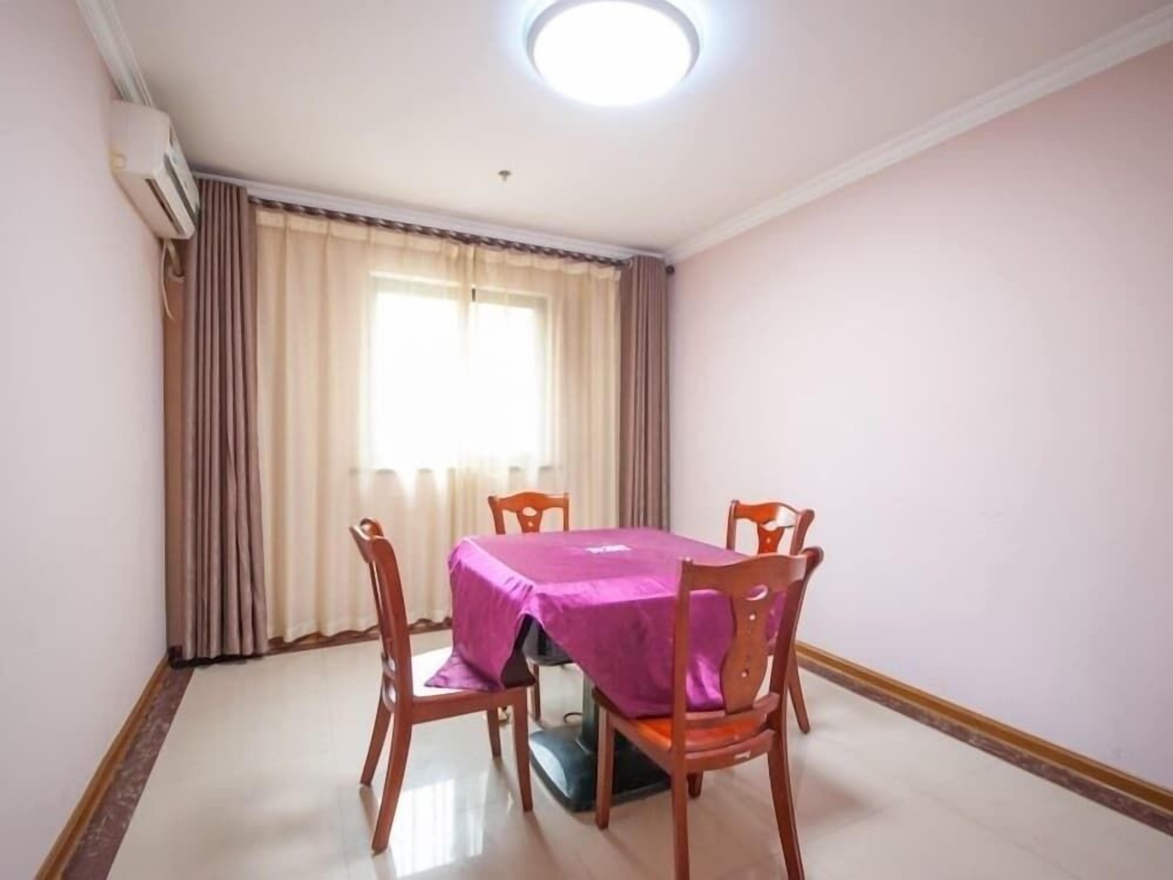 Un coin repas avec une table recouverte d’une nappe violette, entourée de chaises en bois.