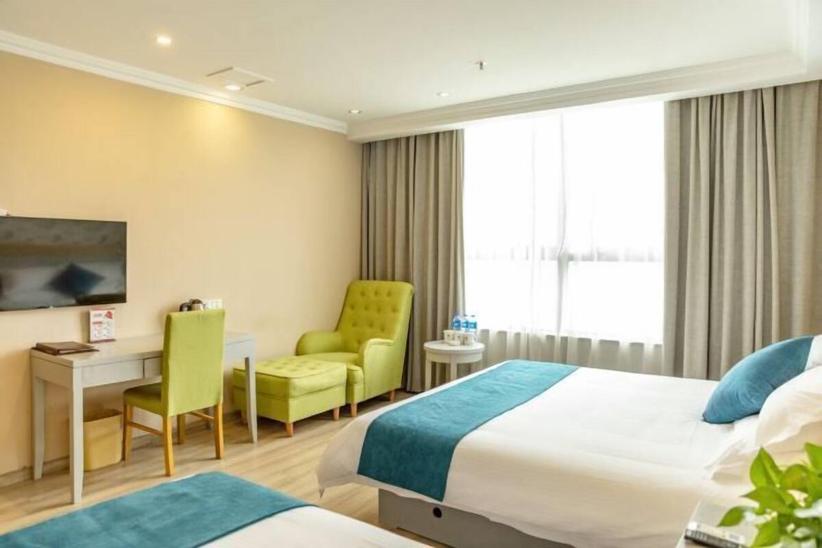 A hotel room with a bed, a desk, a chair, and a TV.