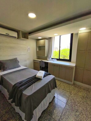 A bedroom with a bed, a desk, and a window with a view of greenery. - MEC Office Hostel (Niteroi)