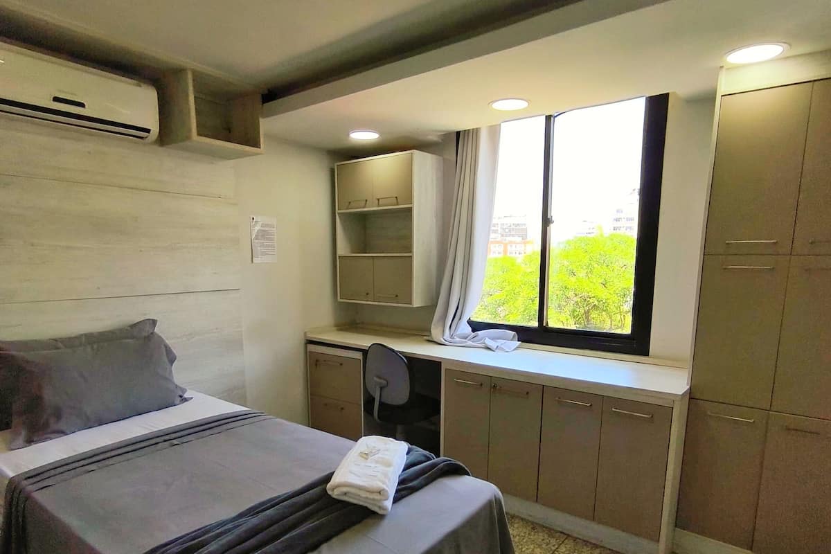 Un dormitorio con cama, escritorio y ventana con vistas a zonas verdes.
