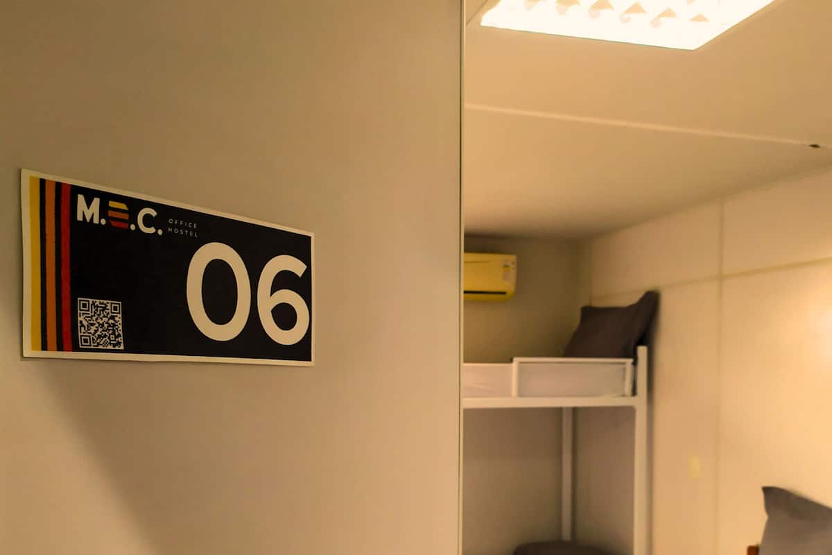 Una habitación con literas, una puerta con el número y una lámpara en el techo.