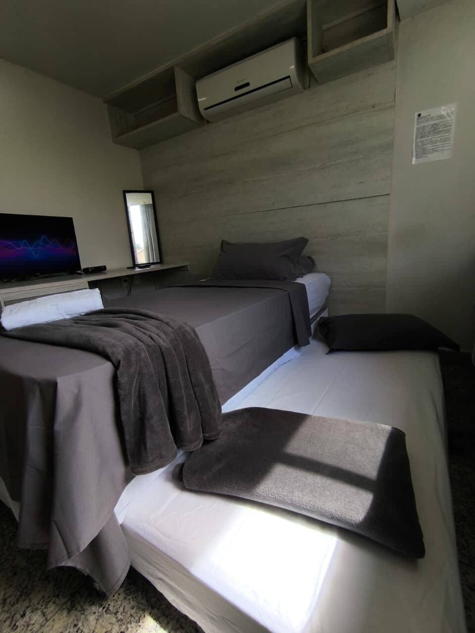A hotel room with two beds, a flat-screen TV, and a wooden headboard.