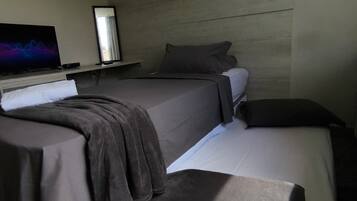 A hotel room with two beds, a flat-screen TV, and a wooden headboard.