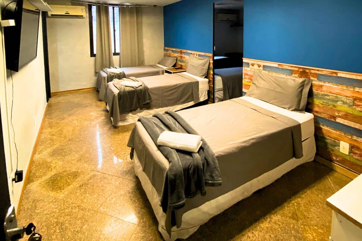 Habitación de hotel con cuatro camas, televisión de pantalla plana, escritorio y baño.