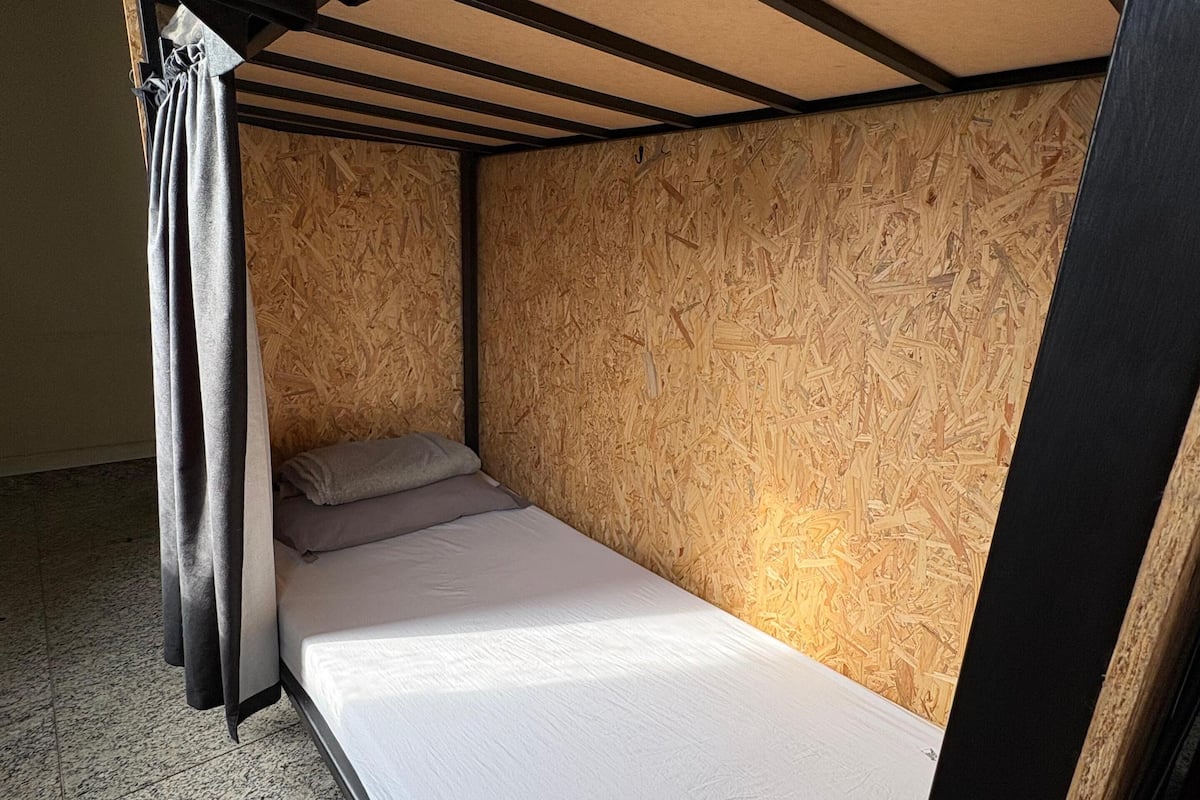 Una cama litera con cabecera de madera y una cortina.