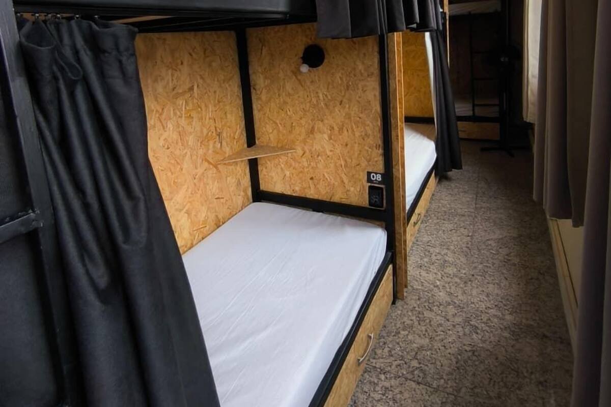 Dormitorio con literas, pared de madera, una cama individual y una lámpara en el techo.