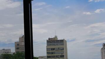 Vista pela janela de um horizonte urbano com edifícios e uma massa de água ao longe.