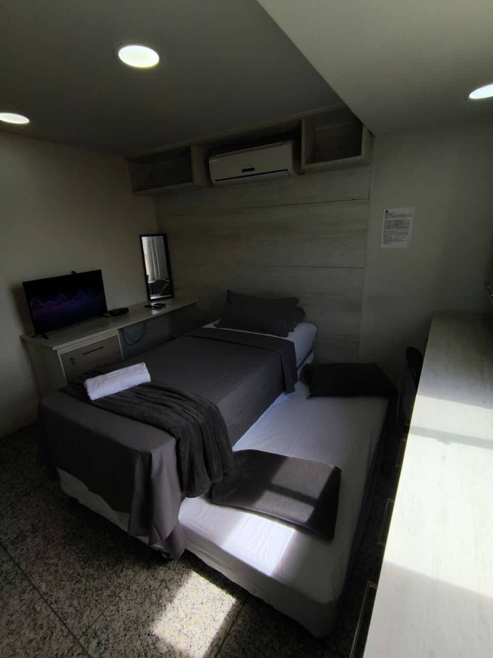 Una habitación de hotel con cama, un escritorio con televisor de pantalla plana y un pequeño rincón de descanso.