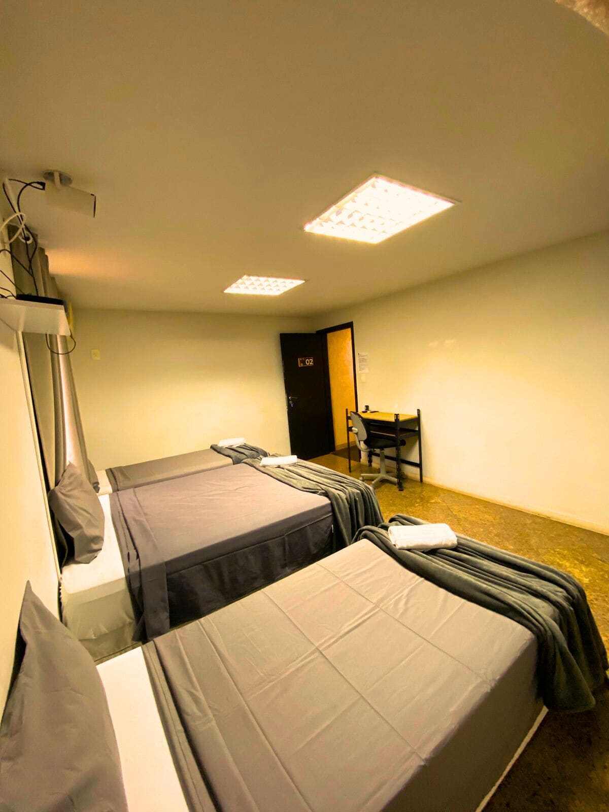 A room with two beds, a desk, and a chair.