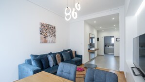 A modern living room with a sofa, a dining table, and a TV. - The Spiritual Athens Apartment (Athens)