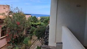 A balcony with a view of a garden and the sea.