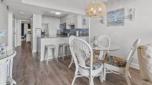 A modern kitchen with white cabinets, a central island, and a hanging light fixture. - Oceanfront 2Bed 2Bath Condo with Large Balcony & Amazing views  (North Myrtle Beach)