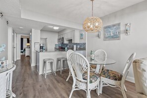 A modern kitchen with white cabinets, a central island, and a hanging light fixture.