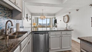A modern kitchen with granite countertops, stainless steel appliances, and a view to the outdoors. - Oceanfront 2Bed 2Bath Condo with Large Balcony & Amazing views  (North Myrtle Beach)