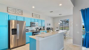 Een moderne keuken met blauwe kastjes, roestvrijstalen apparatuur en een centraal eiland.