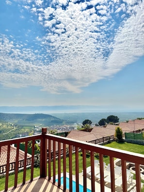 Una terraza con piscina y mobiliario exterior, con vistas a un paisaje de campos escalonados y montañas lejanas.