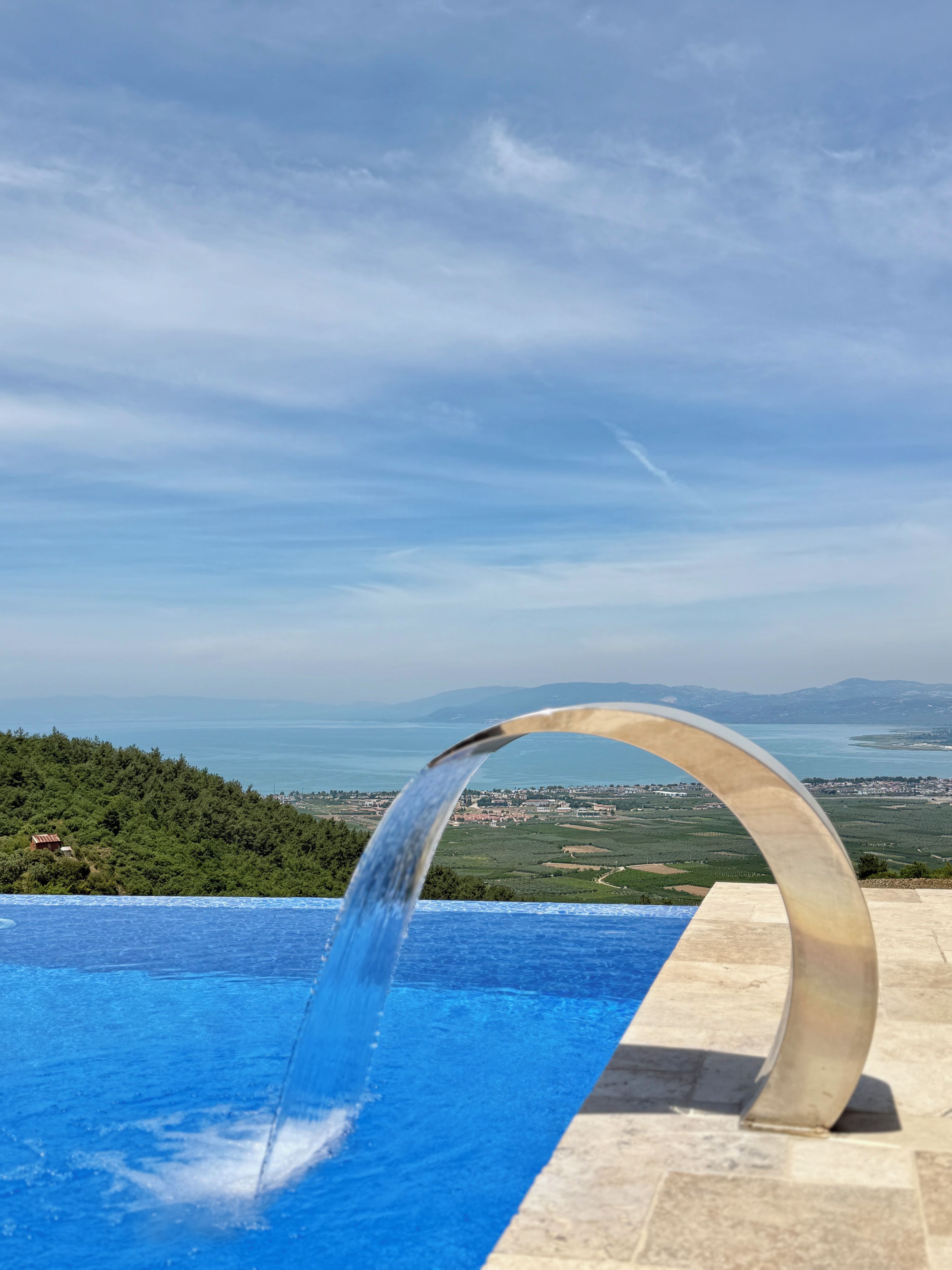 Une piscine agrémentée d’un élément décoratif aquatique et offrant une vue sur un paysage côtier.