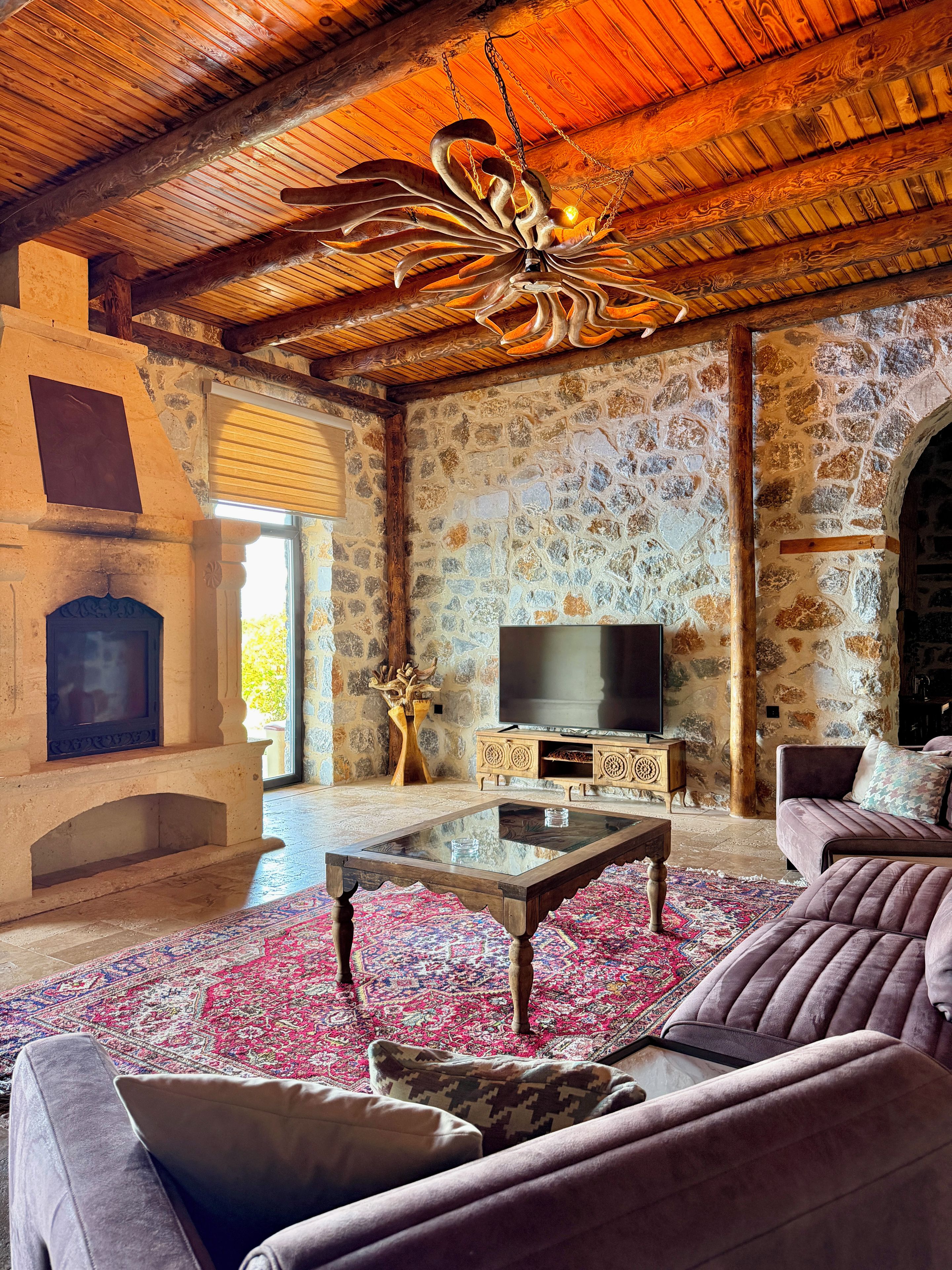 Un salon chaleureux avec une cheminée en pierre, un téléviseur et un canapé confortable.