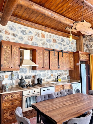 Una cocina rústica con paredes de piedra, armarios de madera y un comedor con mesa y sillas de madera.