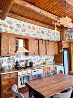 Uma cozinha rústica com paredes de pedra, armários de madeira e um espaço de jantar com mesa e cadeiras de madeira.