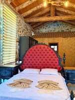 Una habitación con una cama grande, cabecera de madera y pared de piedra.