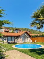 Una casa de piedra con techo de tejas, una piscina y una terraza de madera.
