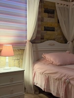 Un dormitorio con cama, mesita de noche, lámpara y pared de piedra.