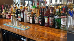 A bar with a variety of liquor bottles and a colorful coaster. - Punch House (Monmouth)