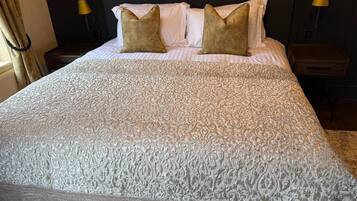 A neatly made bed with a patterned bedspread, two pillows, and two bedside lamps.