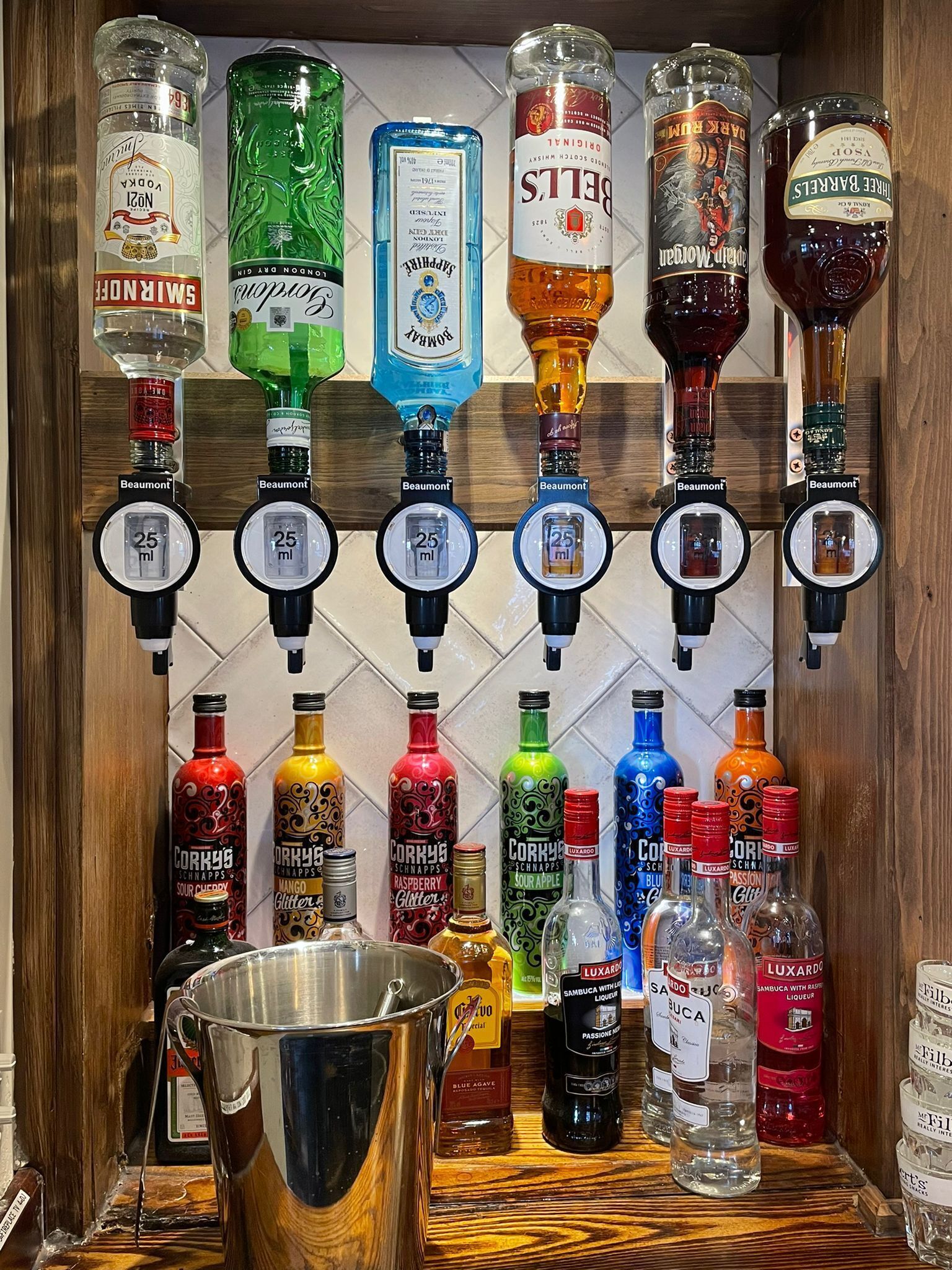 A bar area with multiple liquor dispensers, including brands like Smirnoff, Beamont, and Luxardo.