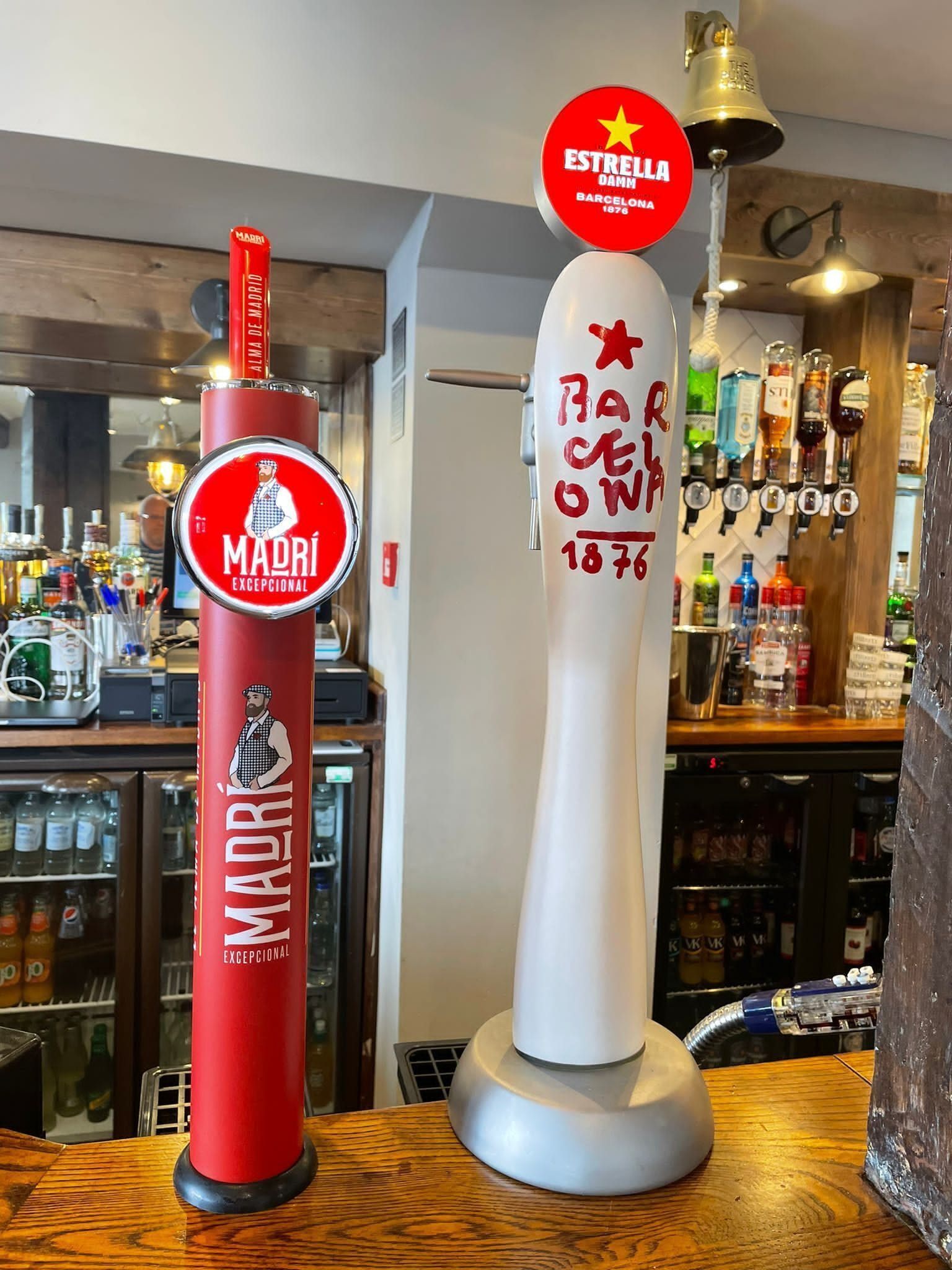 To fadølshaner, hvoraf den ene er mærket 'Madrid Exceptional' og den anden 'Estrella Damm Barcelona 1876'.