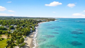 A coastal area with a beach, clear blue waters, and a line of buildings along the shore. - Palm Villa- Rooftop, Pool and Direct Beach Access (Río Grande)