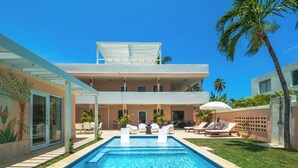 A two-story building with a swimming pool, outdoor seating, and palm trees. - Palm Villa- Rooftop, Pool and Direct Beach Access (Río Grande)