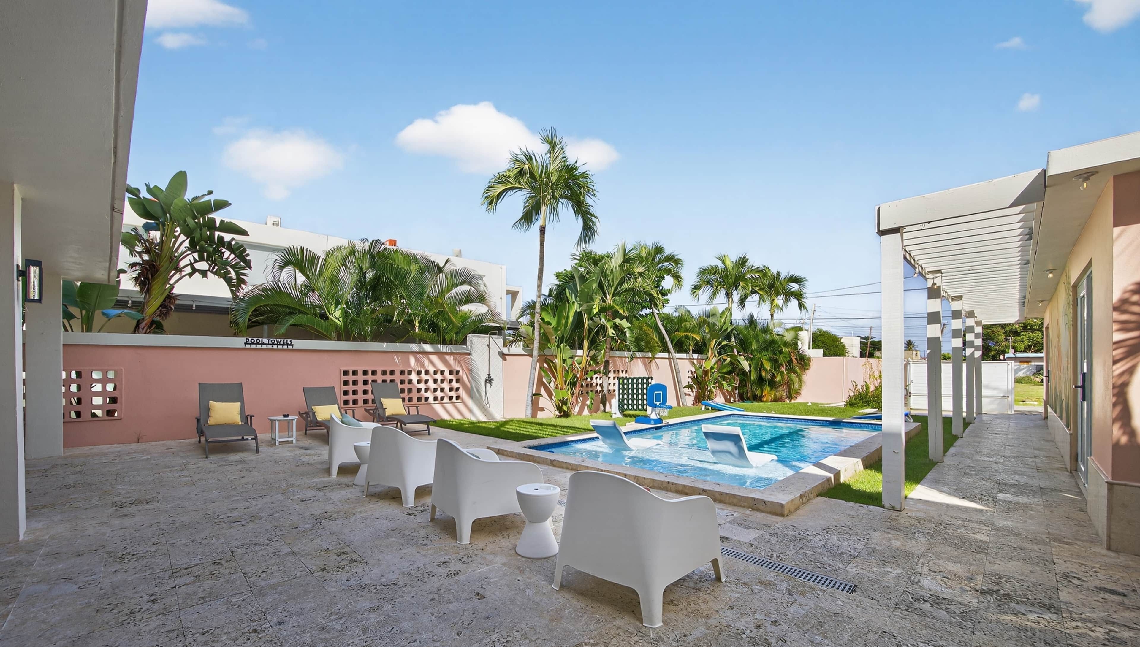 A pool area with lounge chairs, a small pool, and palm trees.