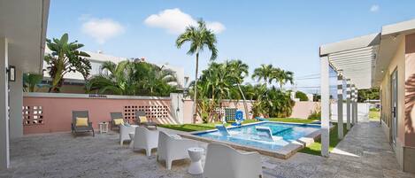 A pool area with lounge chairs, a small pool, and palm trees.