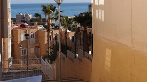 Een woongebied met vrij uitzicht op zee, een lantaarnpaal en een trap die naar een balkon leidt.