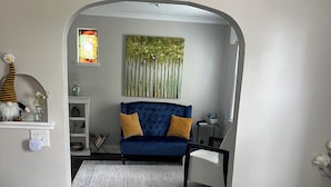 A dining area with a white table, two white chairs, and a vase of orange flowers. - ✽ Charming Cottage ✽ close to College/Town/Station (Wheaton)