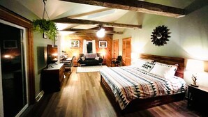 A bedroom with a wooden bed, a desk, a chair, a hanging plant, and a wall clock. - Appalachian Mountain Inn (Mill Run)