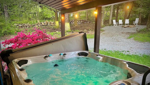 A hot tub with a control panel, surrounded by a wooden deck and outdoor seating. - Appalachian Mountain Inn (Mill Run)