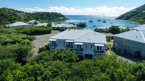 A coastal residential area with houses, a marina, and boats. - Pirates Villa- Beach view with kayaks for Groups (Cruz Bay)