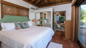 A bedroom with a large bed, a ceiling fan, and a view of the outdoor patio. - Cielo Vista | Pool | Sunsets | Generator (Cruz Bay)
