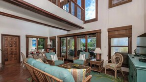 A spacious living area with wicker furniture, large windows, and a view of the outdoors. - Cielo Vista | Pool | Sunsets | Generator (Cruz Bay)