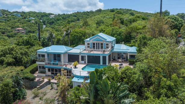 A large, multi-story house with a swimming pool, surrounded by lush greenery and hills. - Cielo Vista | Pool | Sunsets | Generator (Cruz Bay)