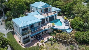 A two-story house with a swimming pool, surrounded by lush greenery. - Cielo Vista | Pool | Sunsets | Generator (Cruz Bay)