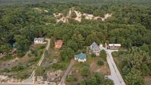 Een landelijk gebied met enkele huizen, omringd door dicht bos. Er zijn wegen zichtbaar en een paar voertuigen.