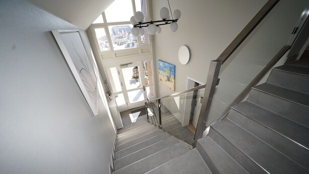 Eine moderne Treppe mit Glasgeländern und Blick ins Freie.